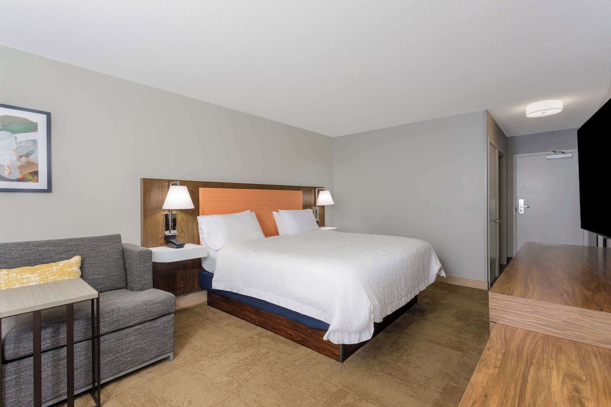 A hotel room with a bed, a sofa, a desk, and a TV.