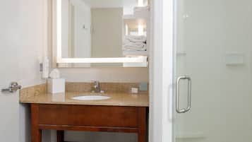 A bathroom with a wooden vanity, a sink, a mirror, and a towel rack.