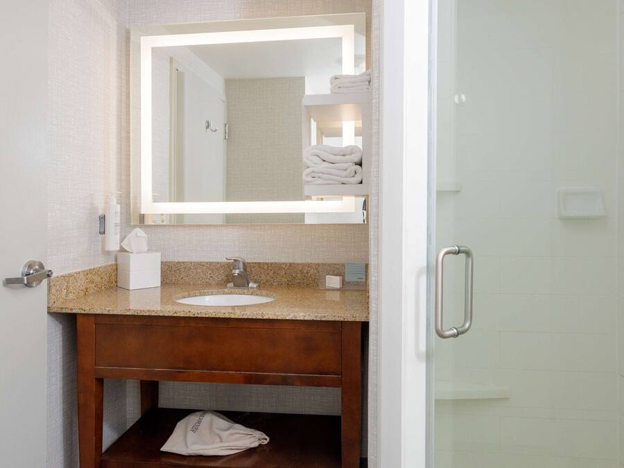 A bathroom with a wooden vanity, a sink, a mirror, and a towel rack.