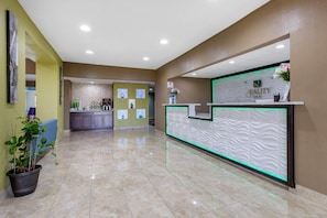 Zona de recepción de un hotel con diseño moderno, un mostrador de recepción y un piso de baldosas limpias.