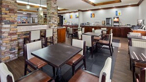 A restaurant with stone pillars, wooden tables, and chairs. - Best Western Inn & Suites (Byron)