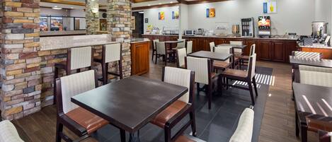 A restaurant with stone pillars, wooden tables, and chairs.