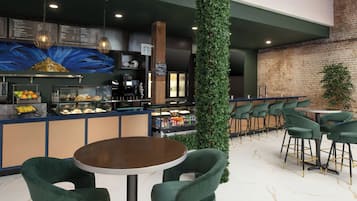 Un café moderno con barra, asientos y una pared decorativa.