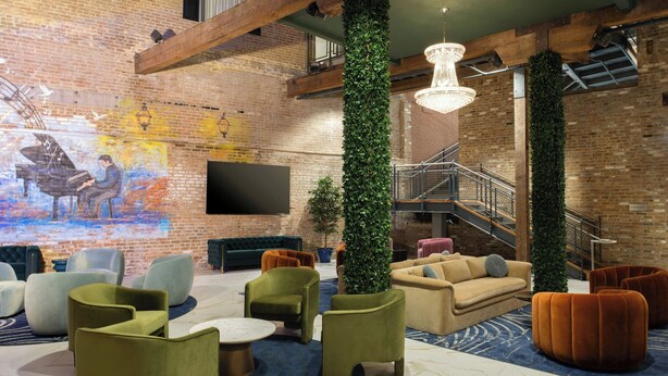 Un área de estar moderna con un mural, asientos cómodos y una escalera.