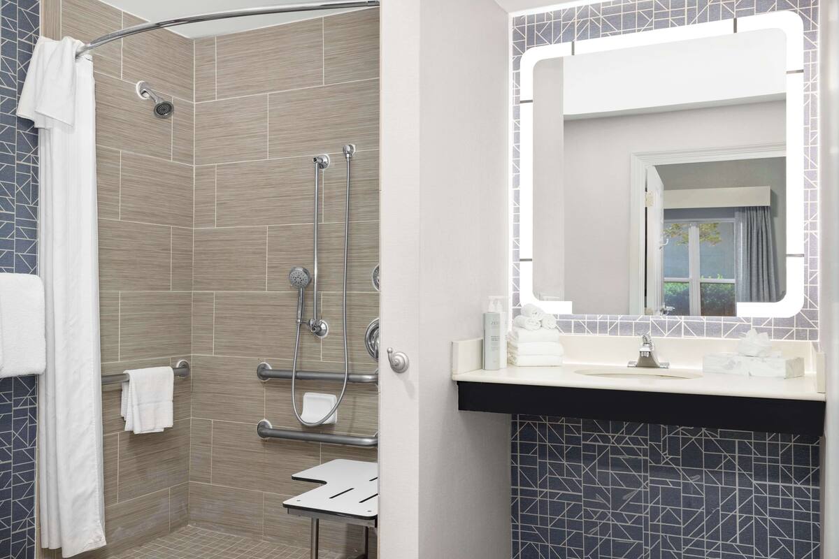 A modern bathroom with a shower, a vanity with a mirror, and a tiled backsplash.