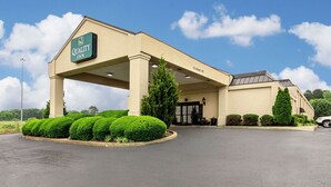 Een Quality Inn met een beige gevel, een overdekte ingang en verzorgde beplanting.