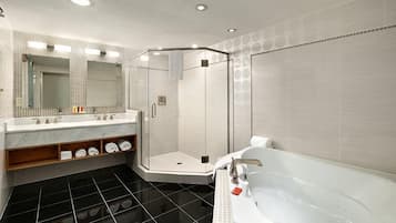 A modern bathroom with a glass-enclosed shower, a large bathtub, and a marble vanity with a mirror.