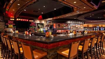 A bar area with a curved counter, multiple seating options, and a sports news display.