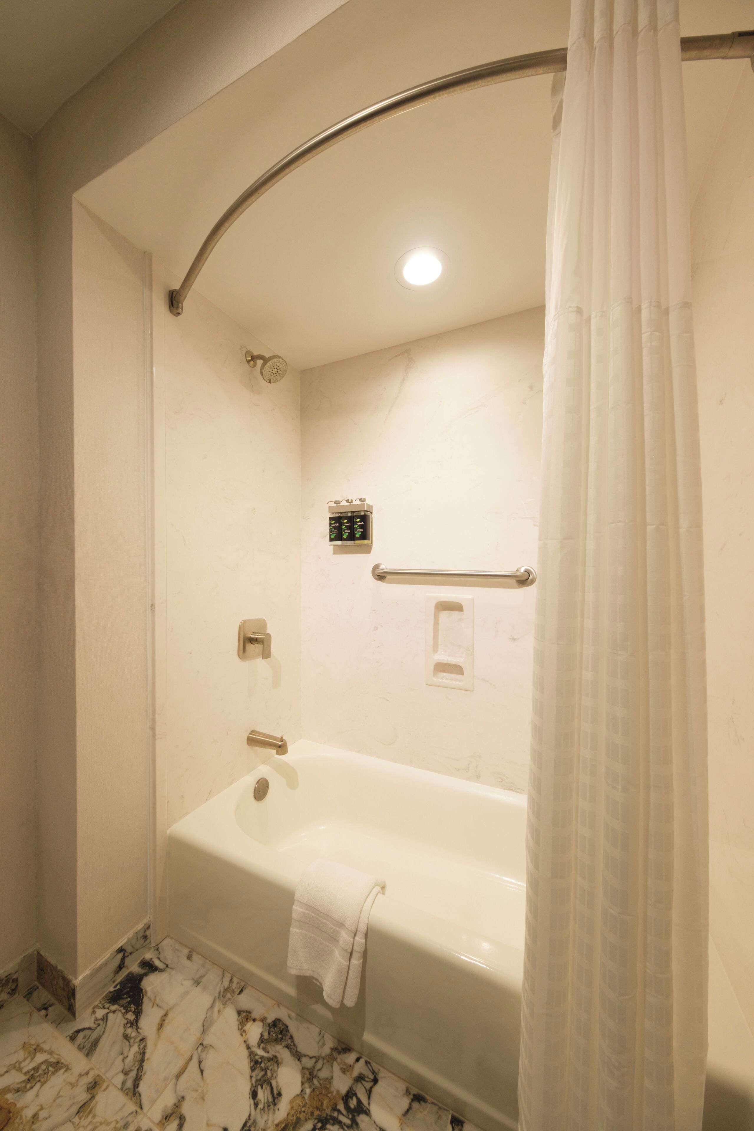 A modern bathroom with a freestanding bathtub, a glass shower enclosure, and a marble-tiled floor.