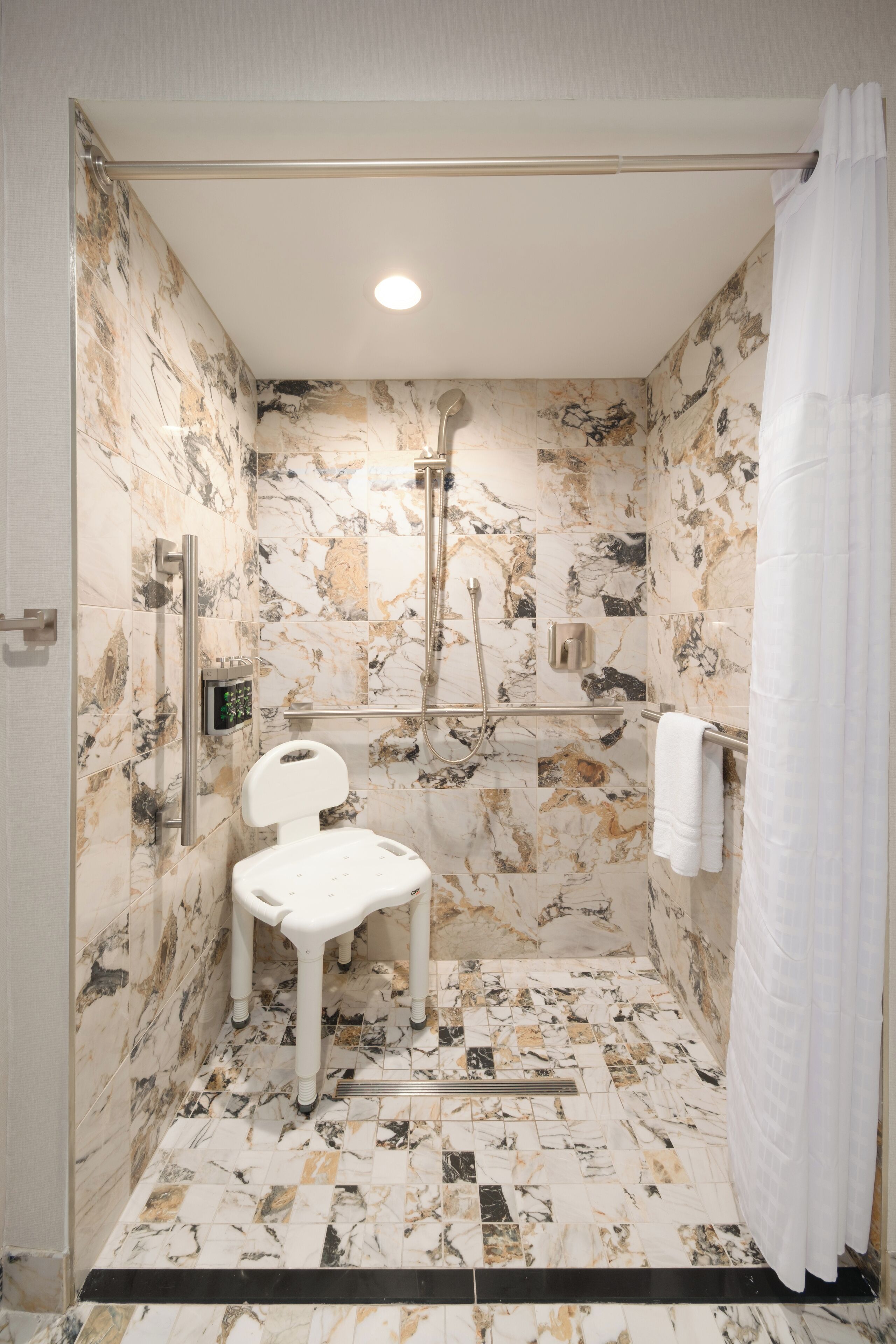 A bathroom with a shower, toilet, and a towel rack.