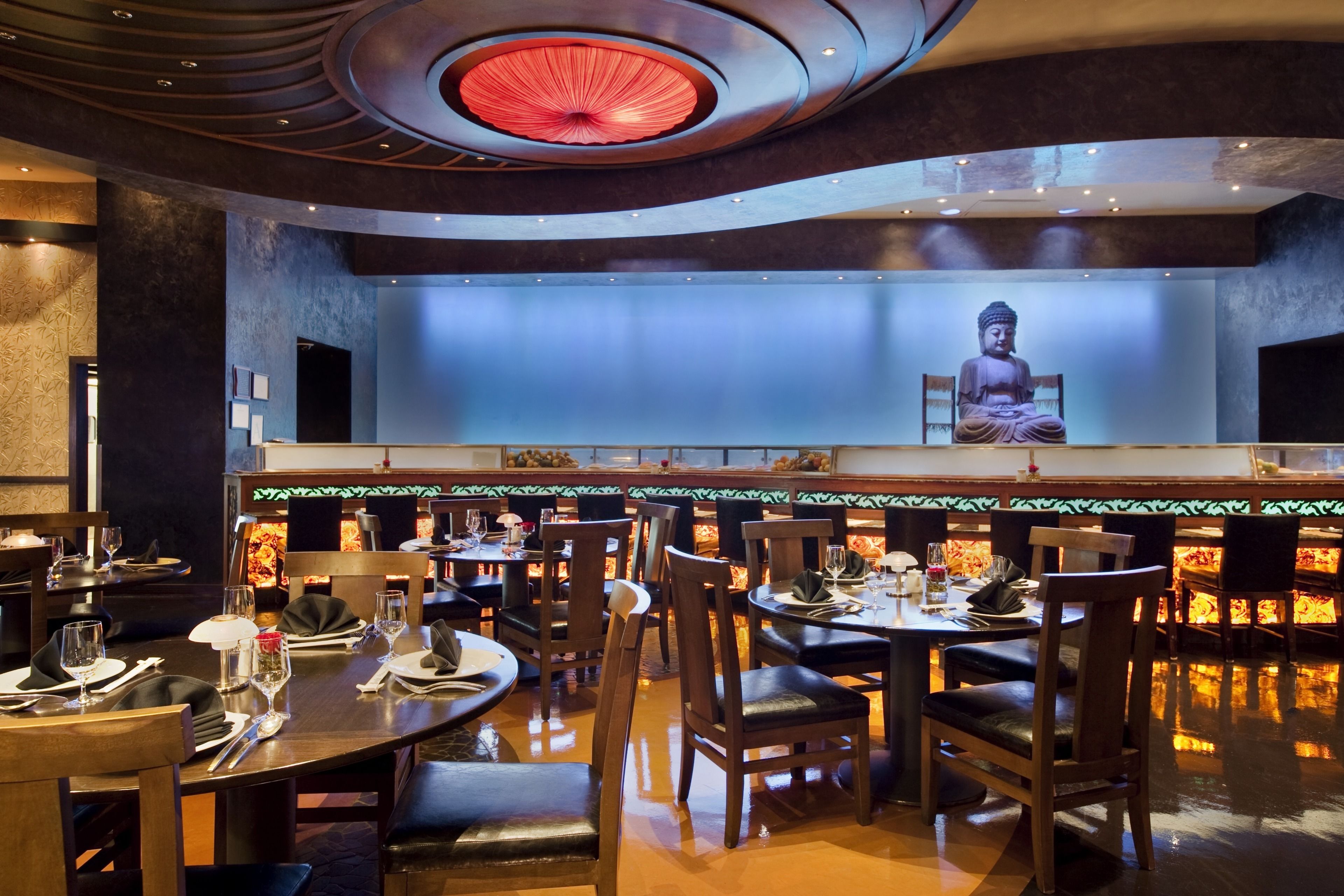Un restaurante con una estatua de Buda, mesas y sillas de madera.