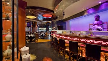 A restaurant with a Buddha statue, wooden decor, and a modern ceiling design.