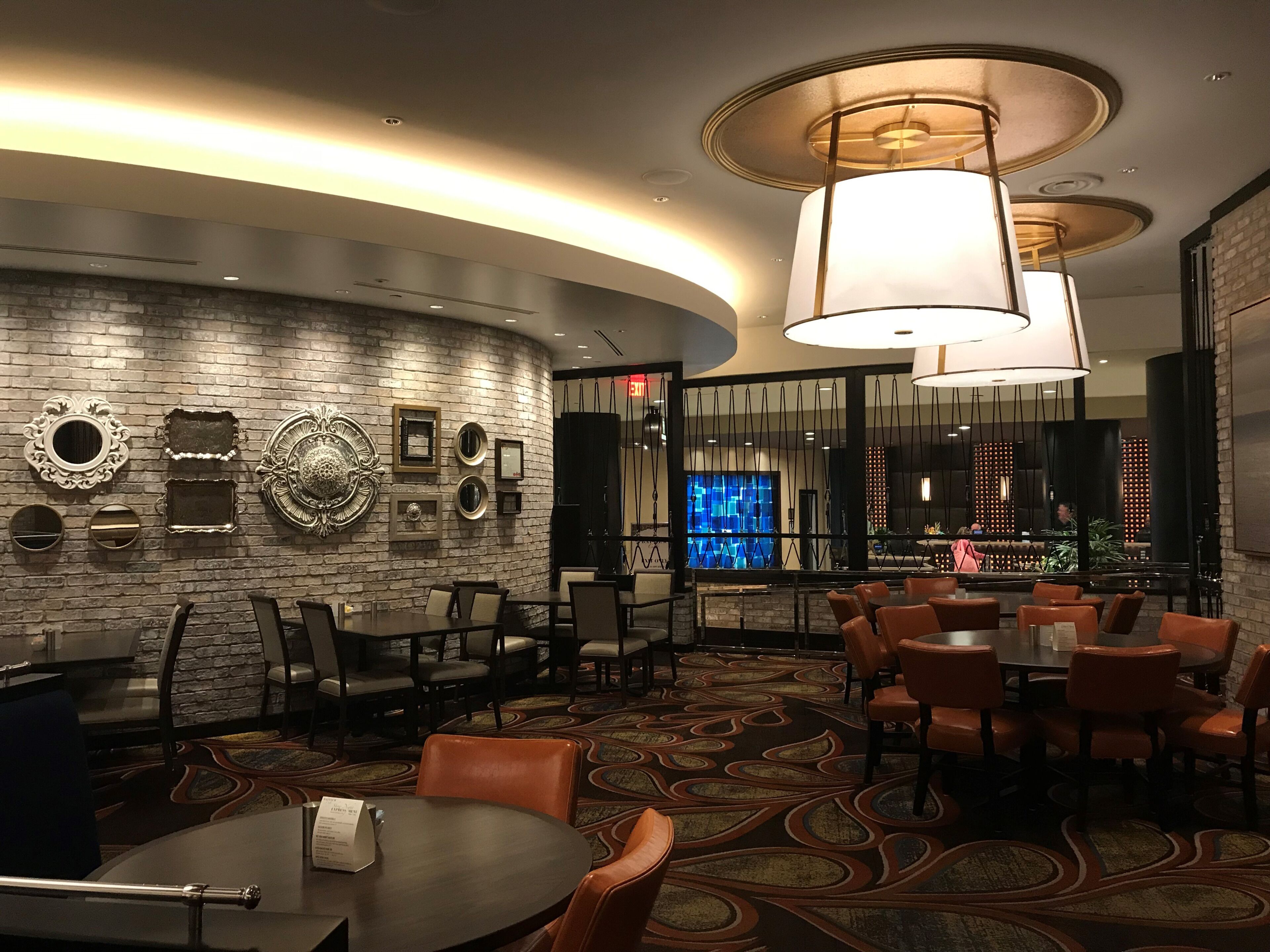 A modern hotel lobby with a curved brick wall, a bar area, and seating arrangements.