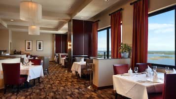 A restaurant with tables set for dining, a bar area, and a view of the water.