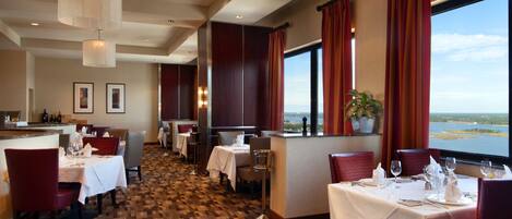 Ein Restaurant mit gedeckten Tischen, einer Bar und Blick auf das Wasser.