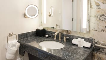 Une salle de bain avec un lavabo en marbre, un grand miroir et un porte-serviettes.