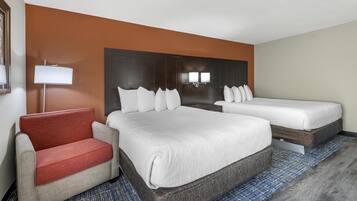 A hotel room with two beds, a sofa, and a lamp.