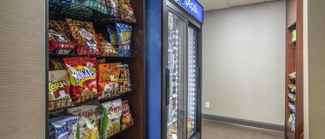 A snack aisle with various chips and snacks, a Pepsi refrigerator, and a tiled floor.