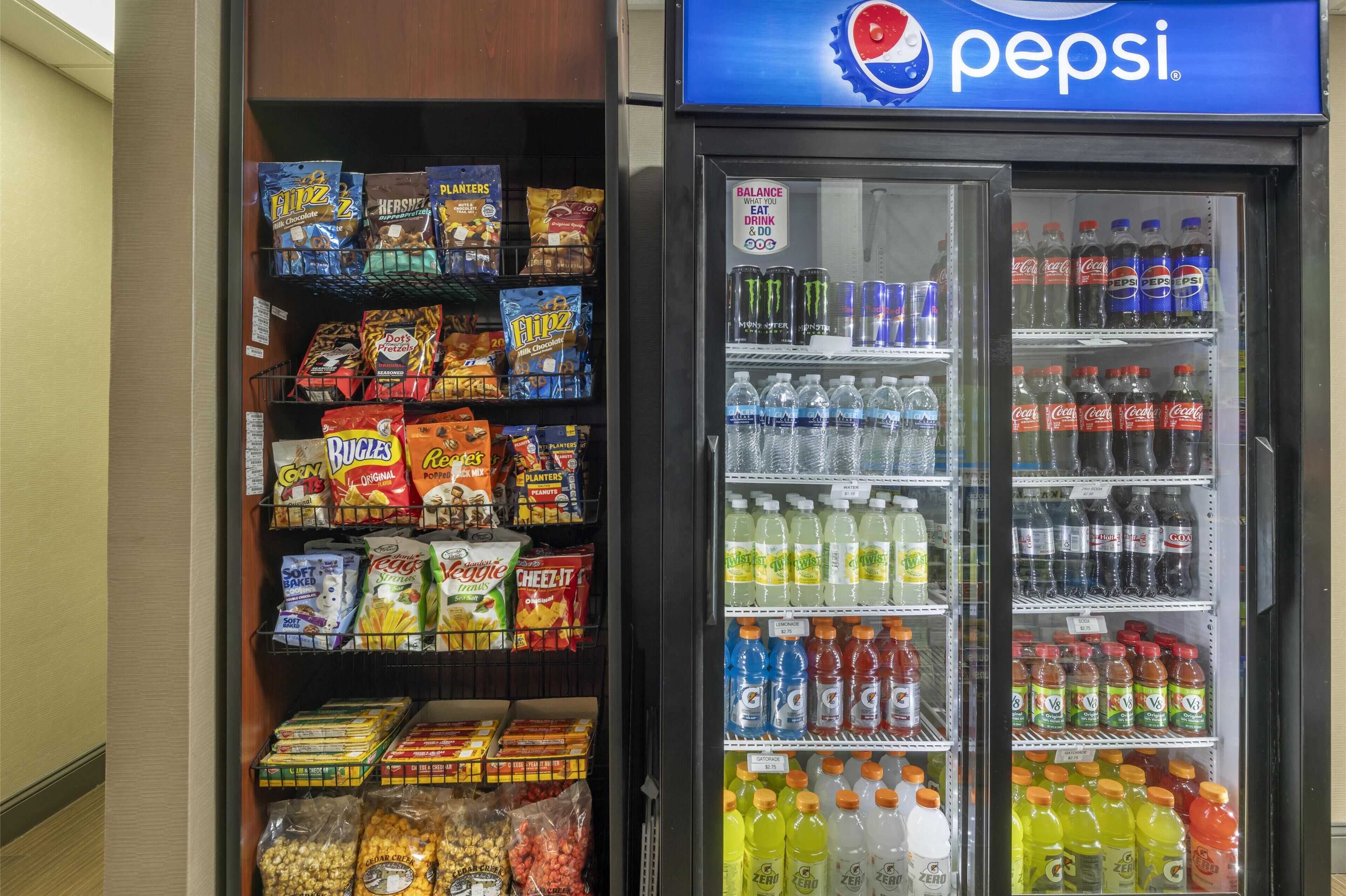 A vending machine stocked with snacks and beverages, including brands like Planters, Fliz, and Pepsi.