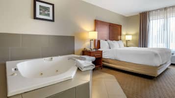 Ein Hotelzimmer mit einer großen Badewanne, einem Bett mit weißen Leinentüchern, einem hölzernen Kopfteil, einem Nachttisch mit Lampe und einem gerahmten Bild an der Wand.