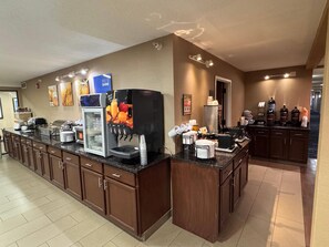 A hotel kitchen with a self-serve coffee station, a refrigerator, and various kitchen appliances.