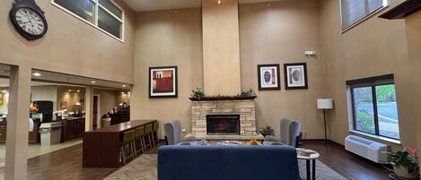 A spacious living area with a fireplace, a chandelier, and a large window.