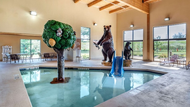 Una piscina interior con una estatua de oso, una escultura de árbol y una estatua de oso sosteniendo un pez.