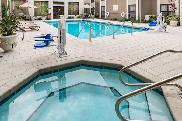 A swimming pool with a tiled deck, lounge chairs, and potted plants. - Hampton Inn & Suites Orlando/East UCF Area (Orlando)