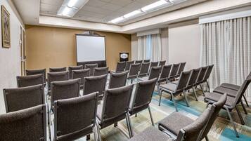 Un salón de conferencias con filas de sillas, una pizarra y un atril.