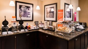 A breakfast bar with waffle makers, coffee machines, and a variety of pastries.