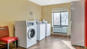 Een wasserette met een wasmachine, droger en een koelkast.