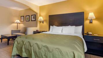 A hotel room with a large bed, two bedside tables, a chair, and wall-mounted lamps.