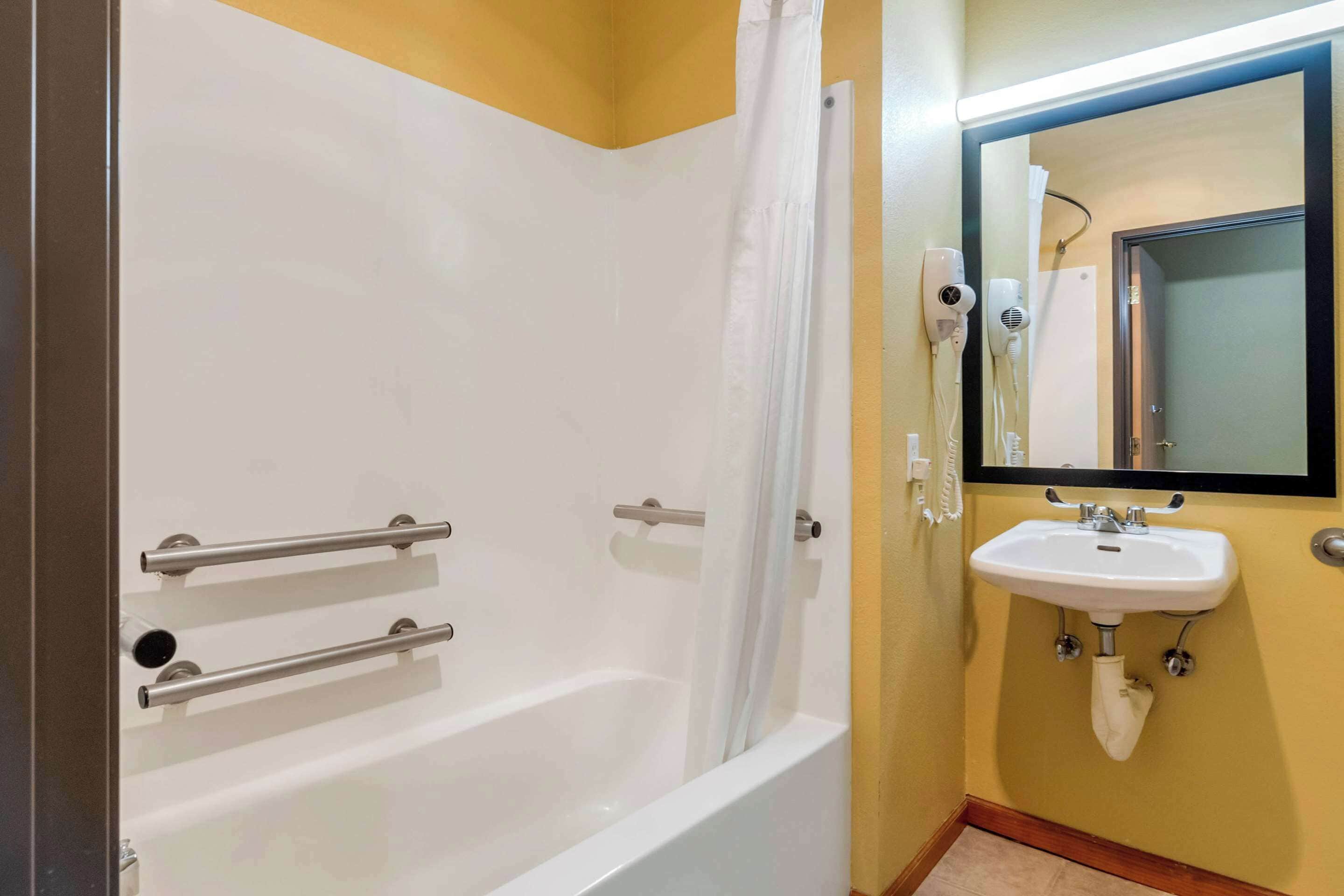 Un bagno con una vasca, un lavandino bianco e uno specchio.