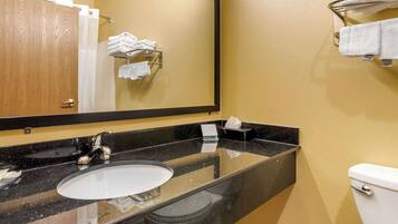 A bathroom with a black granite countertop, a white sink, a mirror, and a toilet.