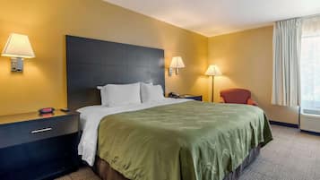 Habitación de hotel con una cama grande, dos lámparas de noche, una mesita de noche con un reloj y una ventana con cortinas.