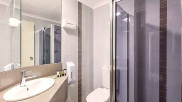A modern bathroom with a sink, mirror, toilet, and glass shower enclosure.