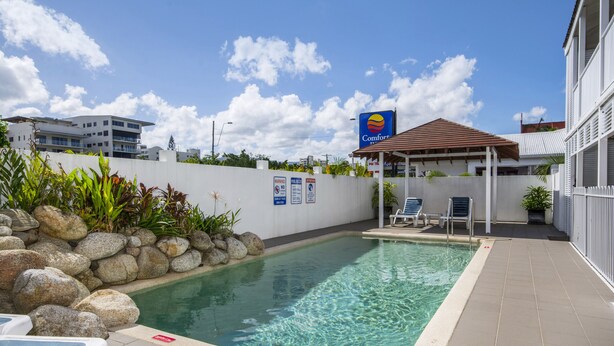 Una piscina con lettini, un'area salotto coperta e il cartello di un Comfort Inn.