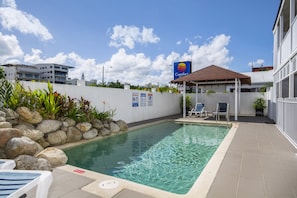 A swimming pool with lounge chairs, a covered seating area, and a Comfort Inn sign. - Comfort Inn Cairns City (Cairns)