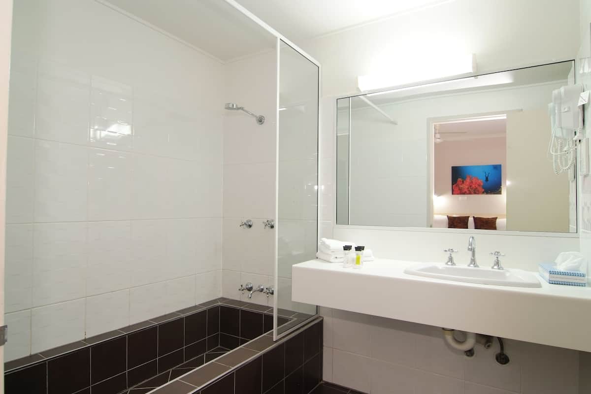 A bathroom with a white sink, mirror, and shower.