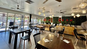 Un ristorante con posti a sedere interni, ventilatori a soffitto e illuminazione decorativa.
