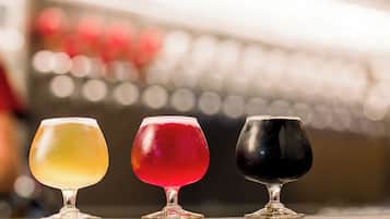 Three glasses of different colored beverages on a bar counter.