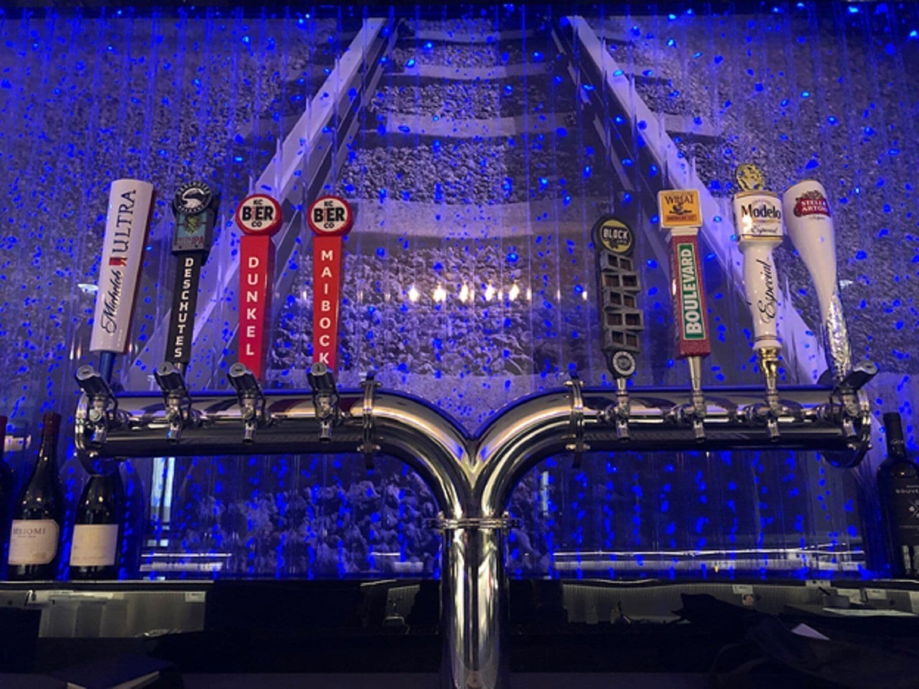 A tap system with multiple beer brands, including Modelo, and a backdrop of a crowd.