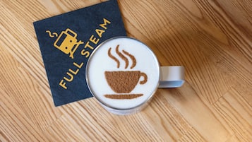 A cup of coffee with a steam design, a napkin with 'FULL STEAM' text, and a wooden table.