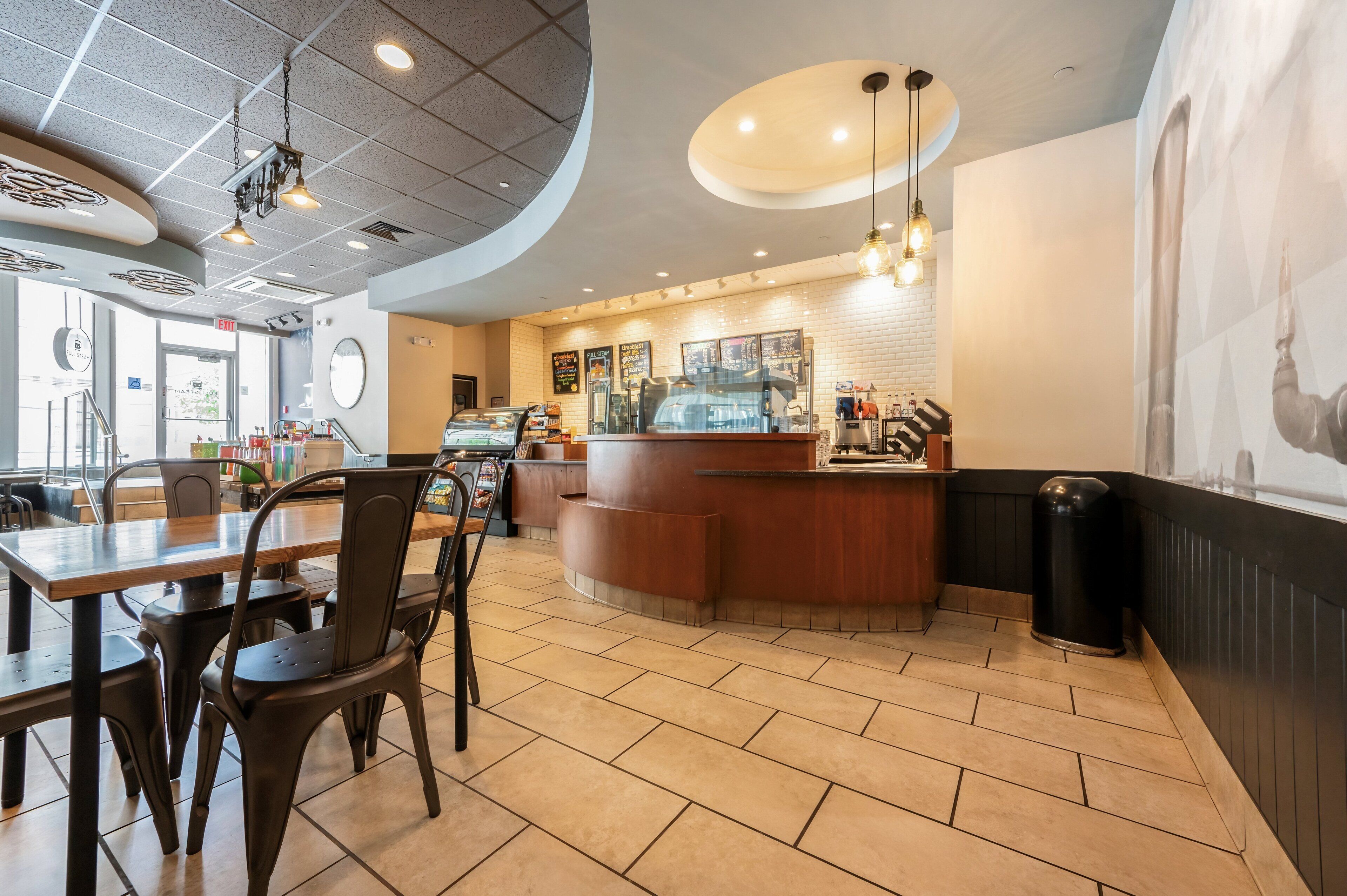 A restaurant interior with a counter, seating area, and a tiled floor.