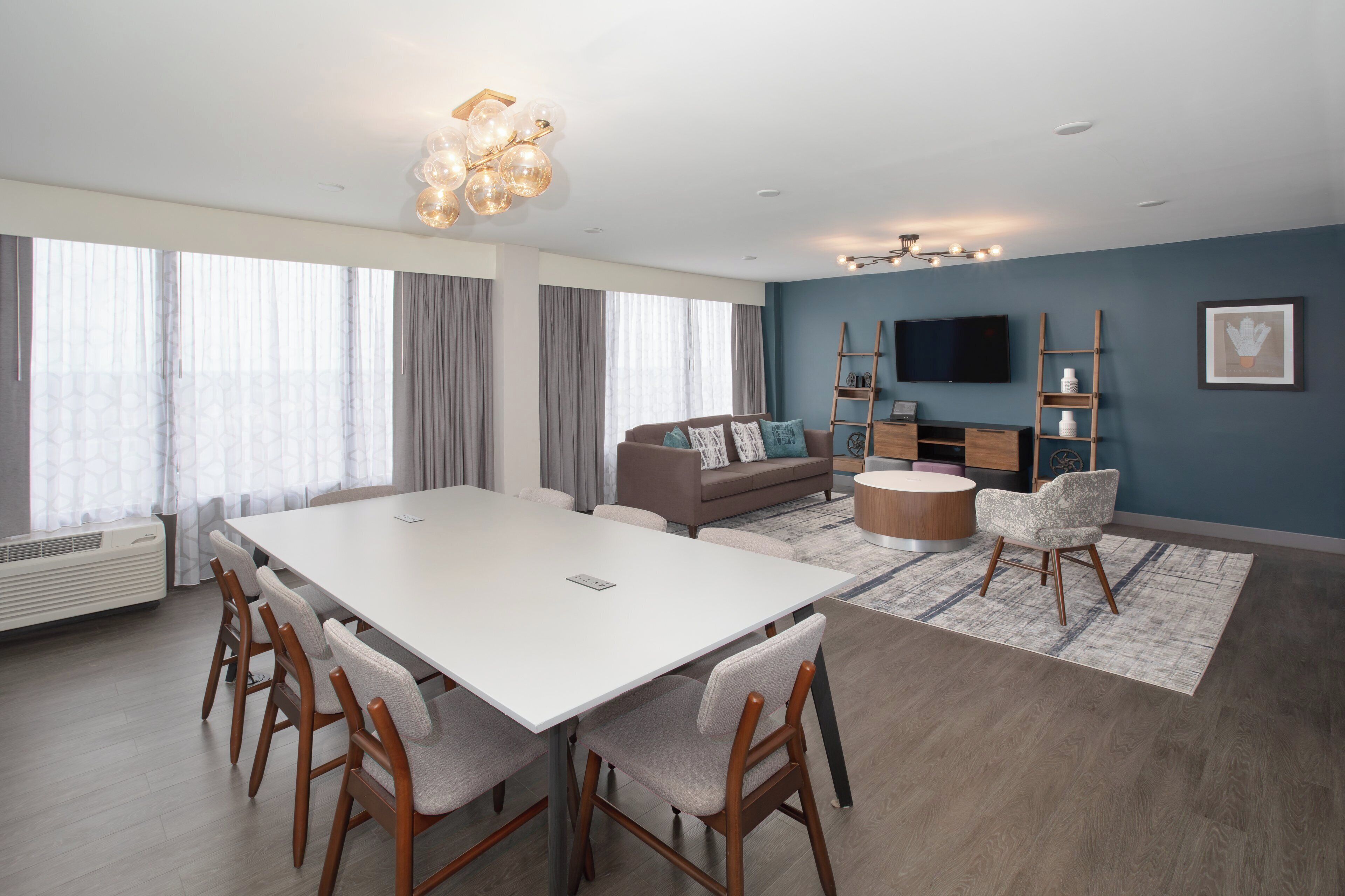 A modern living room with a white dining table, sofas, and a TV.