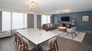 Ein modernes Wohnzimmer mit einem weißen Esstisch, Sofas und einem Fernseher.