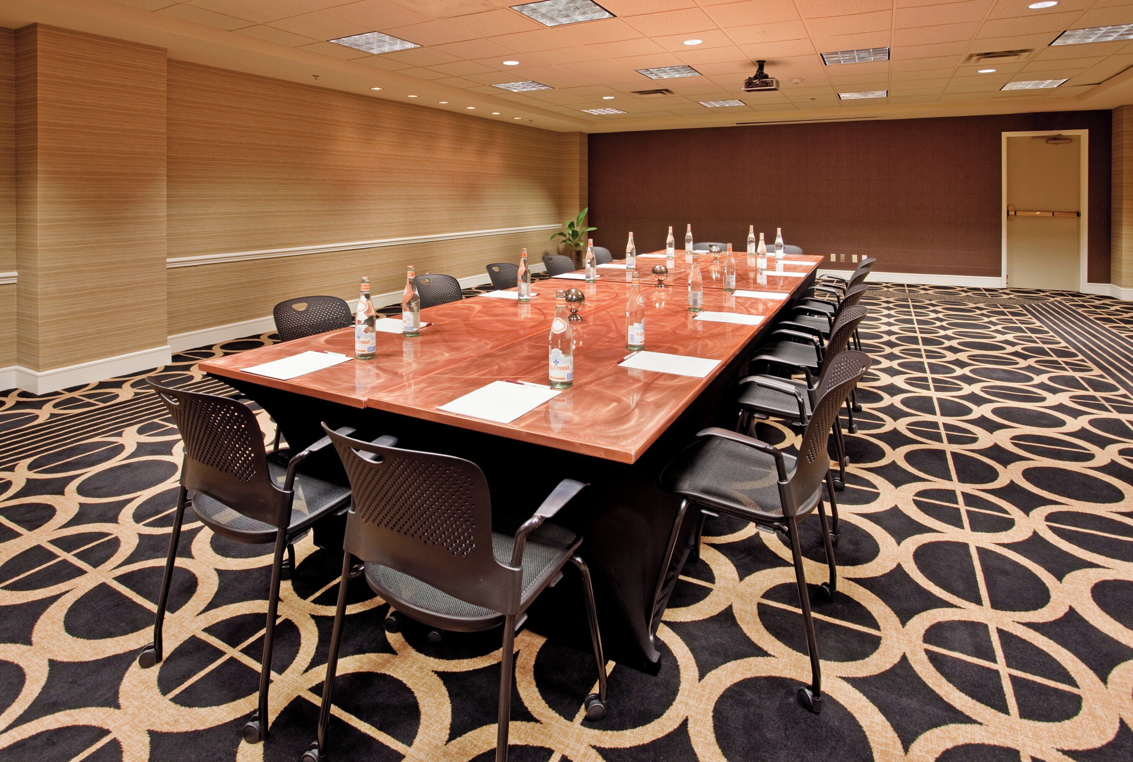 Une salle de conférence avec une longue table, des chaises et des bouteilles d’eau.
