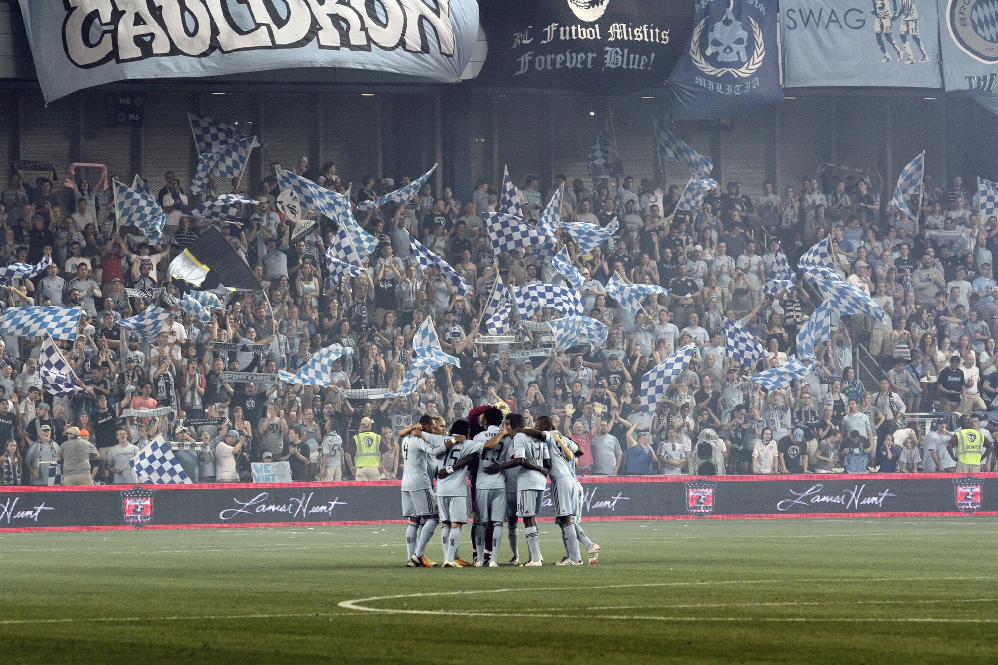 A stadium filled with spectators holding blue and white checkered flags, indicating a sports event.