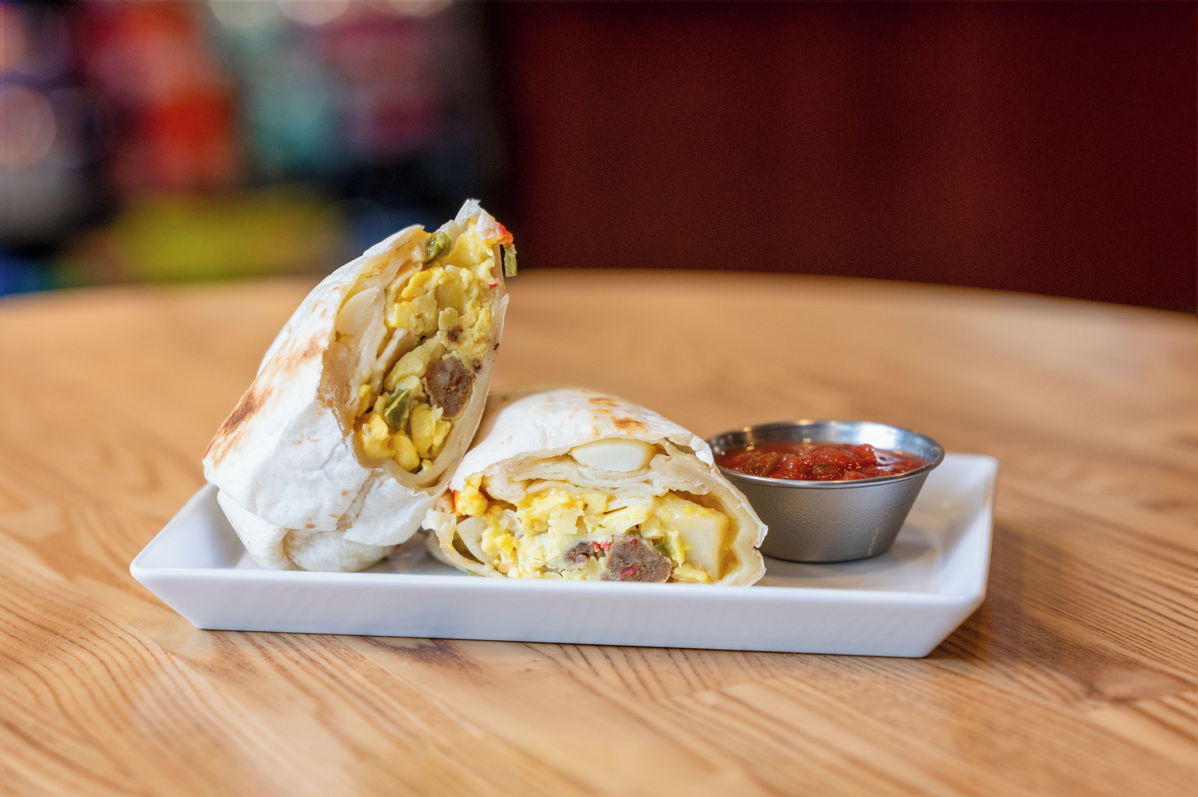 Ein halbierter Burrito auf einem weißen Teller mit Salsa.