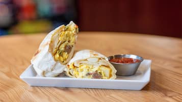 Ein halbierter Burrito auf einem weißen Teller mit Salsa.